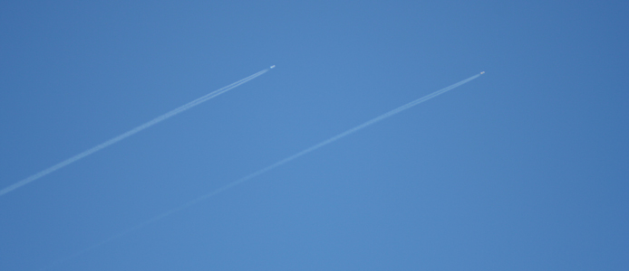 zwei parallel fliegende Flugzeuge am blauen Himmel